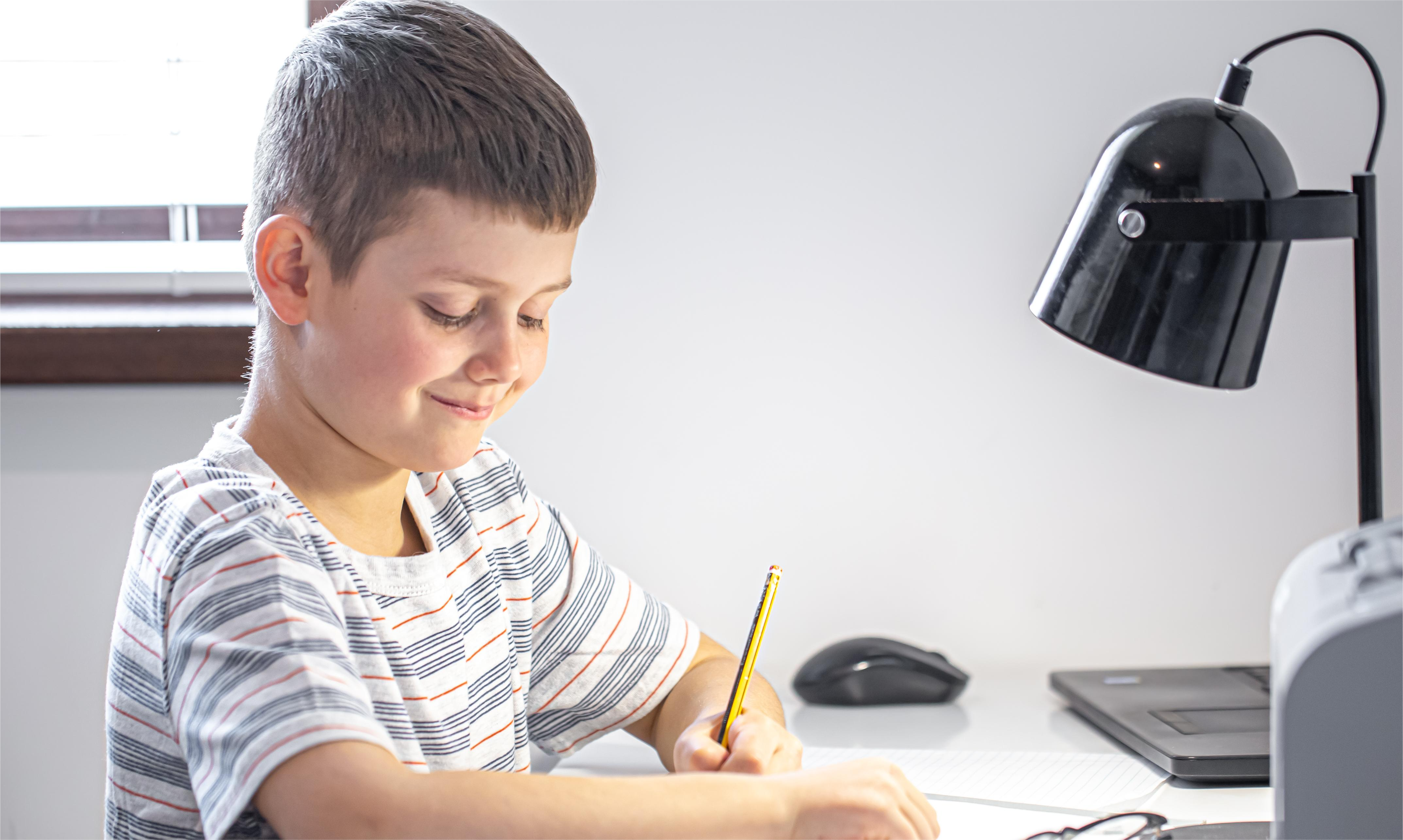 elementary-school-student-sits-table-with-lamp-writes-something-notebook(1).png